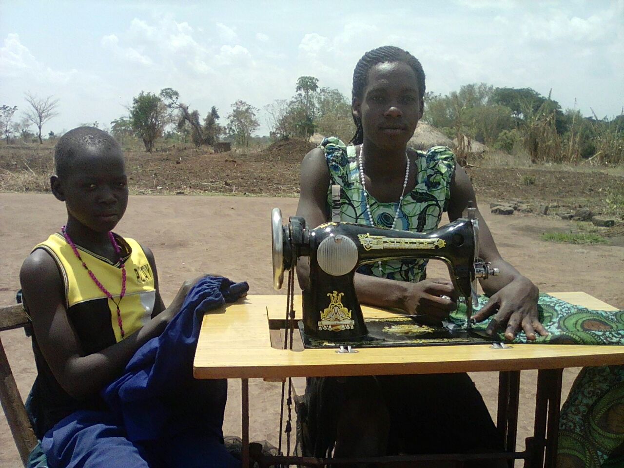 Stella Adongo at work whilst a boy waits to have his school uniform adjusted